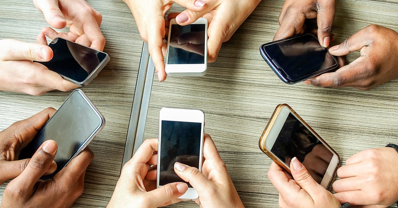 Foto van zes mensen die bezig zijn met hun mobiele telefoon. Ter illustratie van het CCV-dossier Online ordeverstoringen.