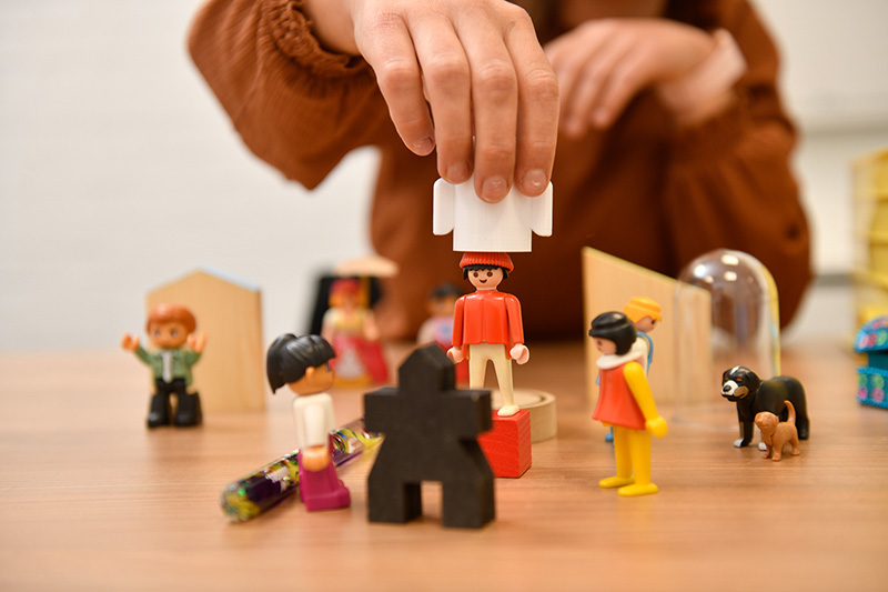 Persoon speelt met speelgoedpoppetjes. Ter illustratie van Landelijk Outreachend Team