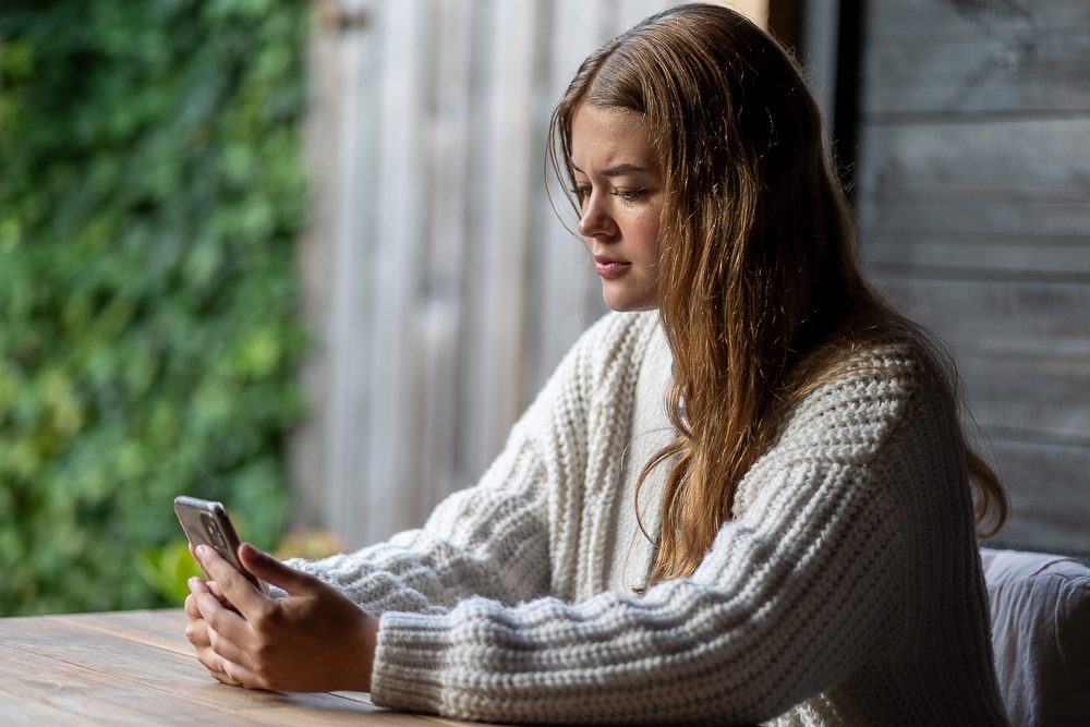 Een tienermeisje kijkt naar haar mobiele telefoon.