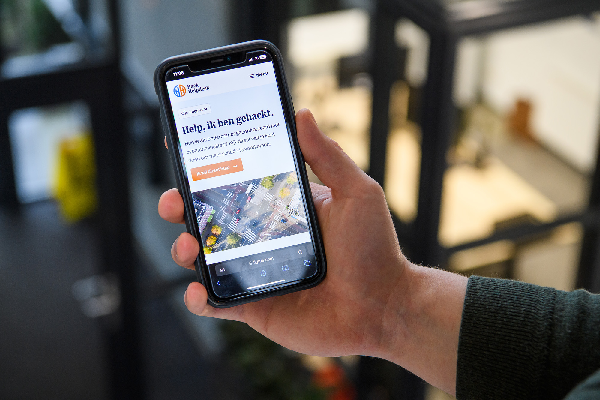 Hand houdt mobiele telefoon vast waarop site van de HackHelpdesk is te zien.