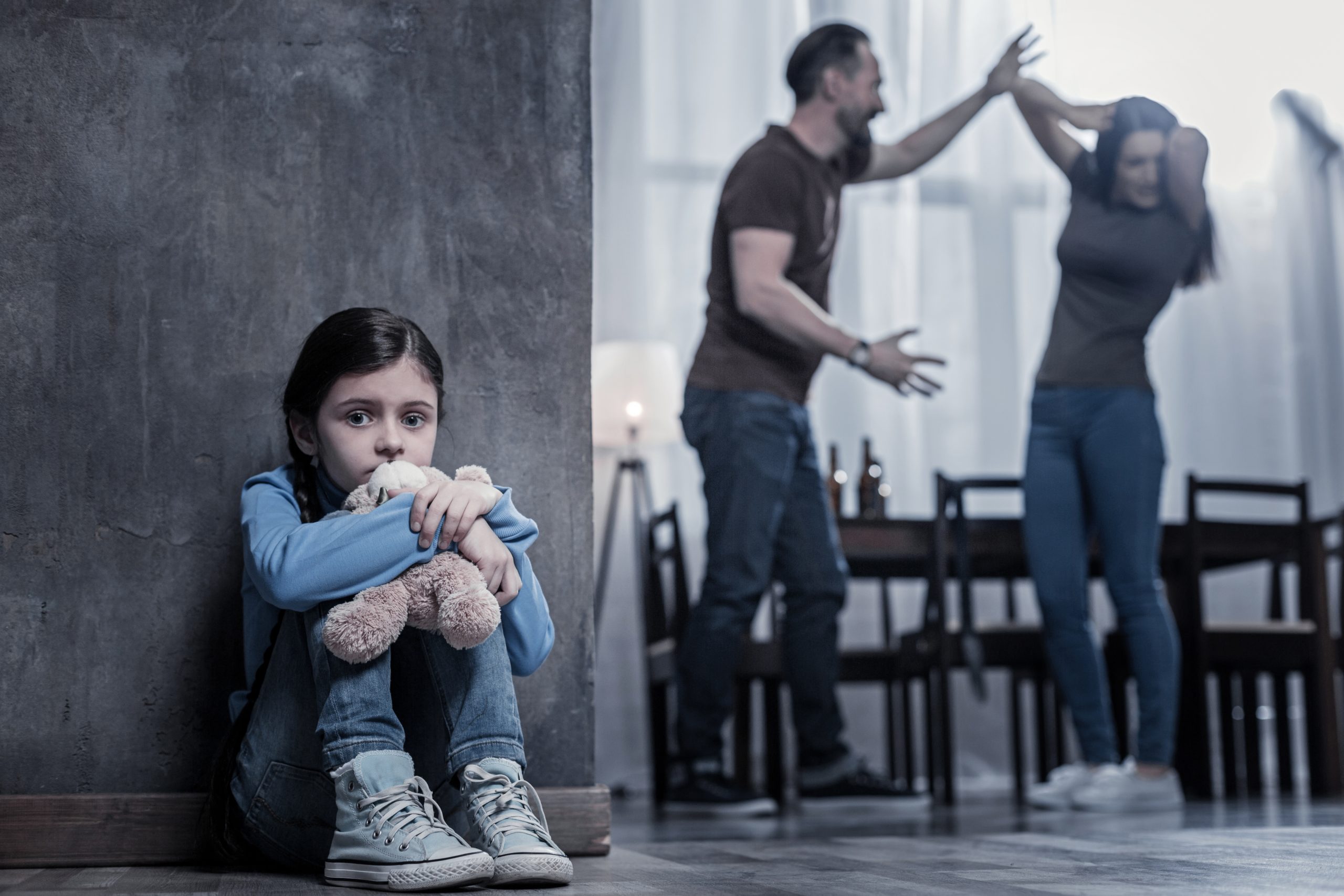 Verdrietig kind terwijl ouders op de achtergrond ruziek maken.