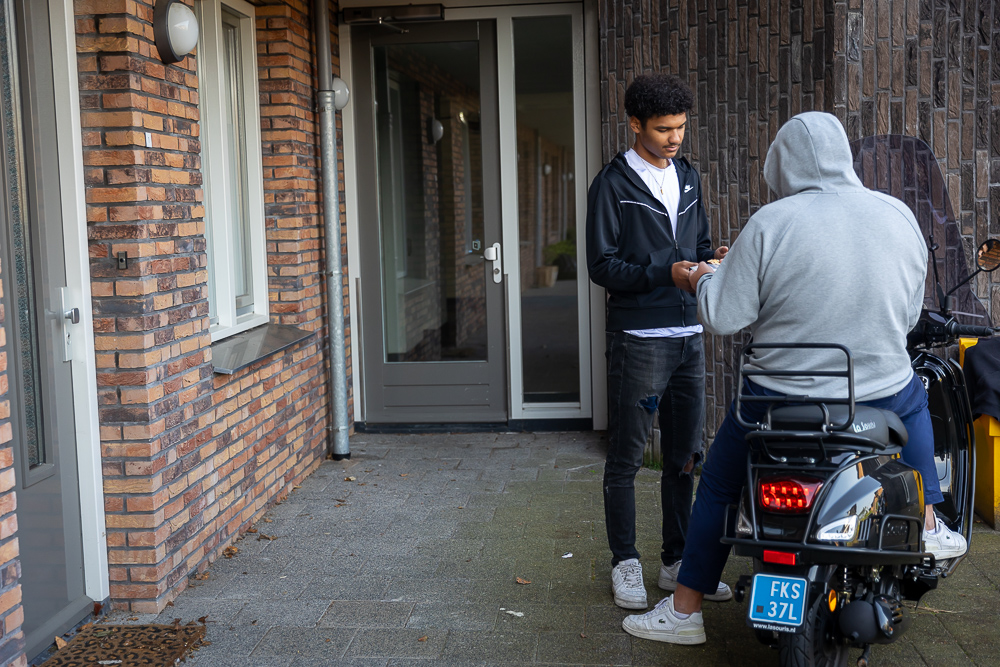 Twee schimmig personen overhandigen elkaar iets.