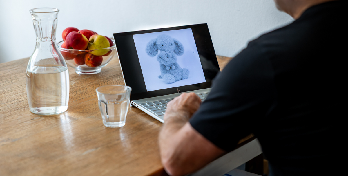 Man achter laptop met ene knuffel op beeldscherm.