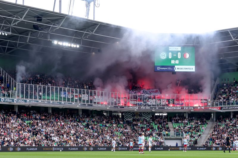 Voetbalsupporters steken vuurwerk af in stadion.