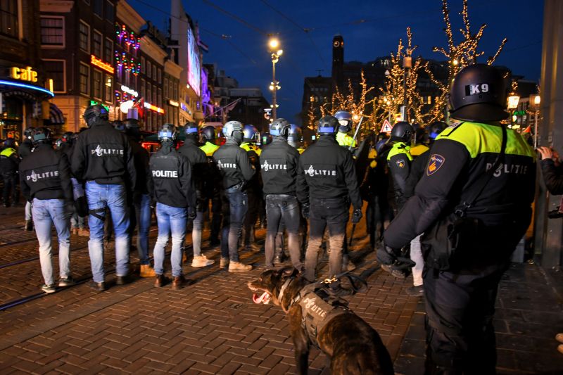 Agenten met politiehonden bij rellen.